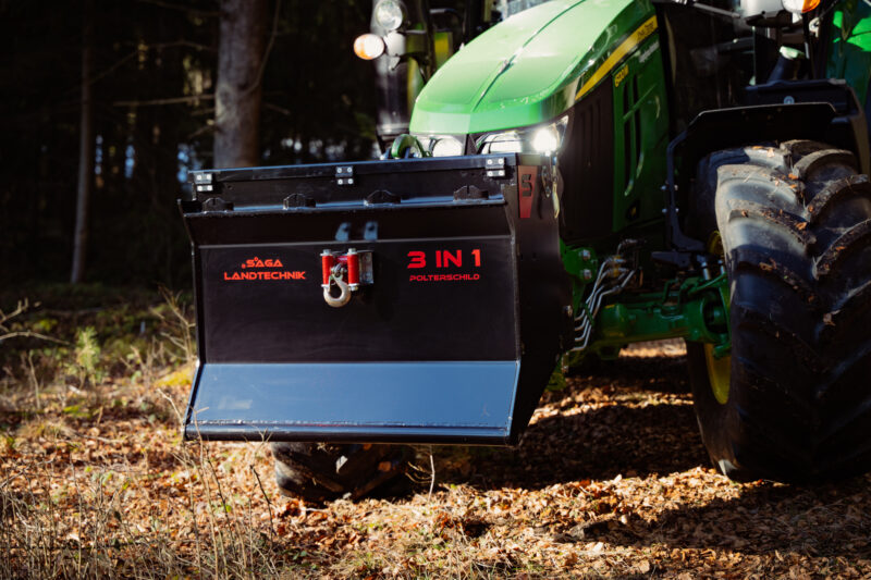 Grüner Traktor mit Frontanbaugerät mit der Aufschrift „3 IN 1“ auf einem Waldboden.