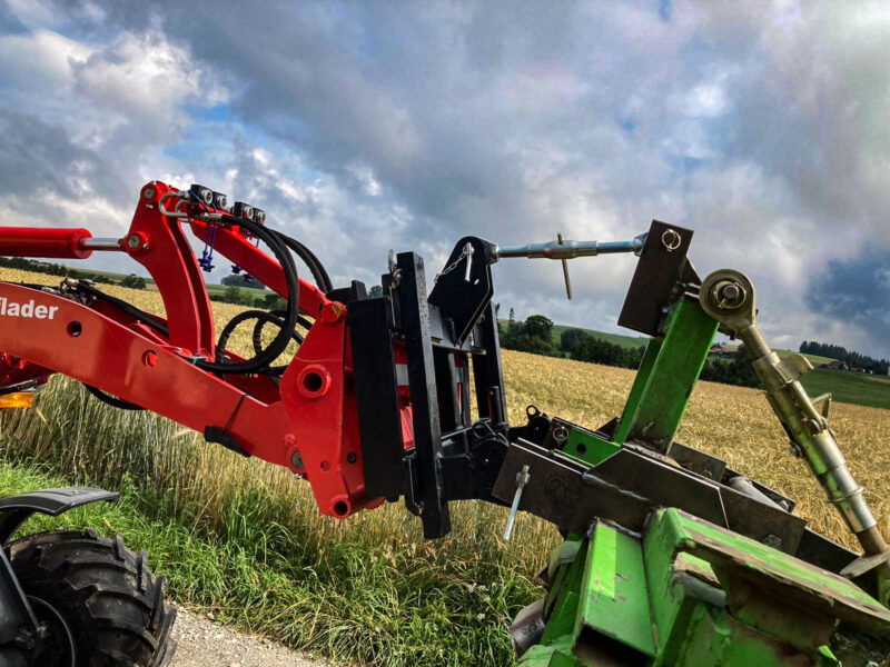 Zwei Traktoren mit Frontladern stehen sich auf einem Feld unter einem bewölkten Himmel gegenüber.